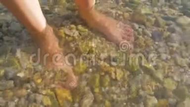 人脚站立在非常清澈的海洋水，海水。 男人的腿上覆盖着水和可见的屁股。 游客腿
